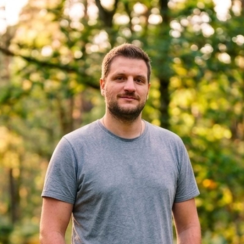 Stefan Lang im grauen T-Shirt vor sonnigem Wald